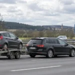 Samochód osobowy ciągnący lawetę z autem na niemieckiej autostradzie