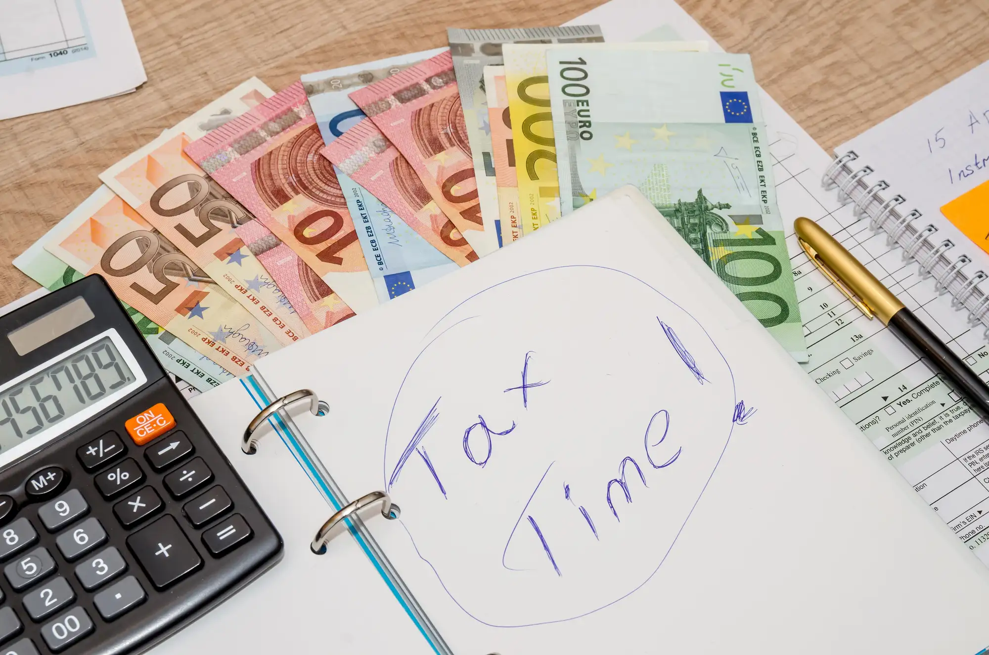 Banknoty euro, kalkulator i kartka z napisem Tax Time