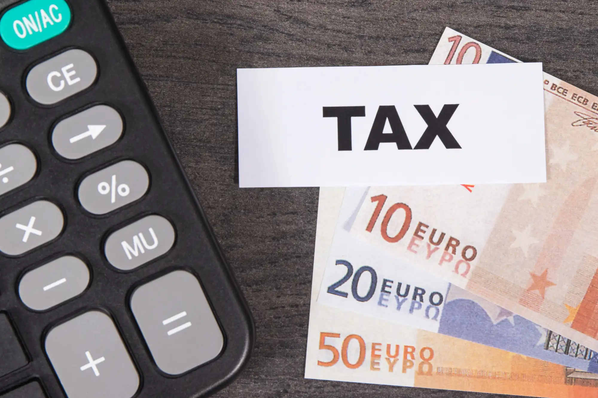 Kalkulator, banknoty euro i kartka z napisem TAX