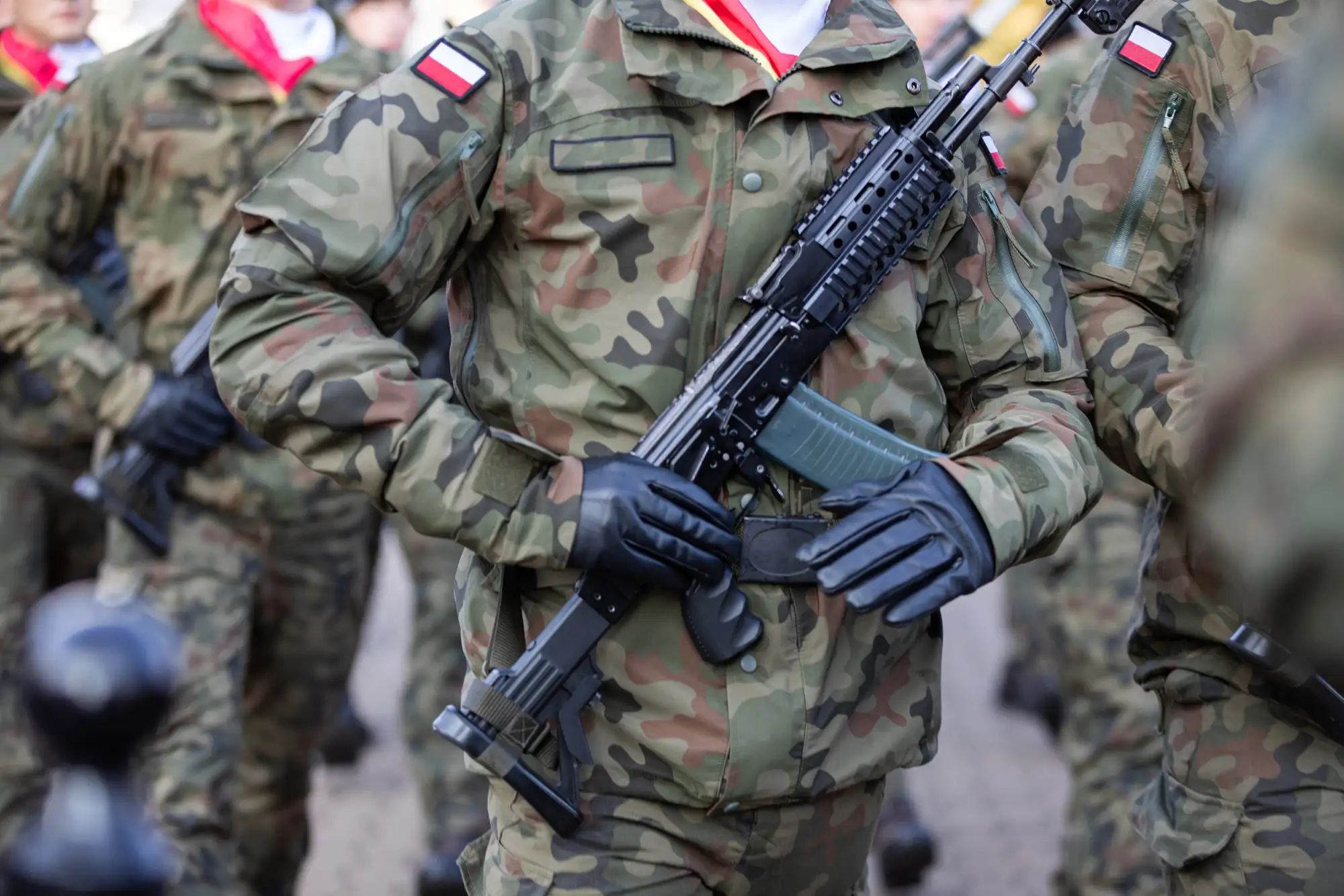 Polscy żołnierze w mundurach z biało-czerwymi naszywkami podczas marszu