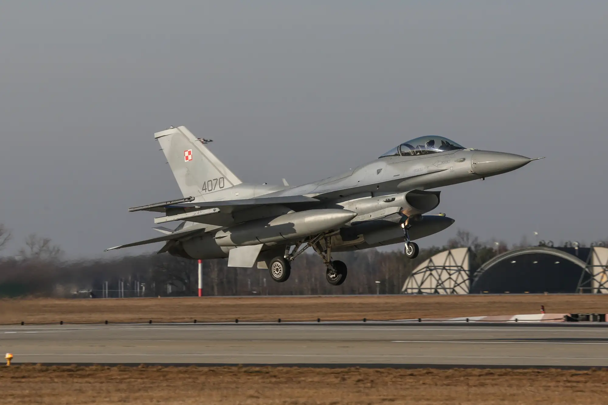 Polski myśliwiec F-16 z wysuniętym podwoziem podczas podejścia do lądowania.