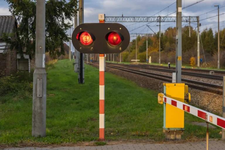 Czerwone światła i opuszczony szlaban na przejeździe kolejowym w Polsce
