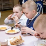 Dzieci jedzą obiad przy stole w szkolnej stołówce