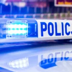 Niebieskie światła radiowozu polskiej policji i napis POLICJA na belce sygnalizacyjnej.