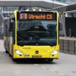 Żółty autobus przegubowy U-OV w pobliżu dworca Utrecht Centraal w Holandii.
