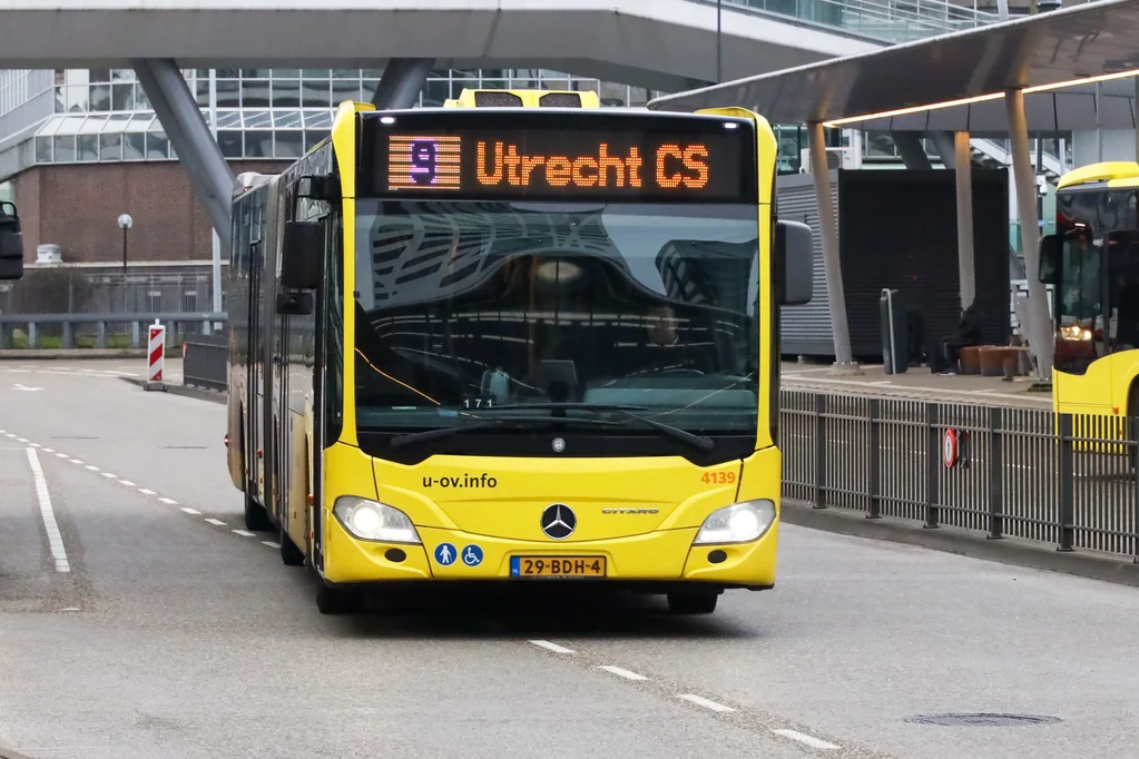Żółty autobus przegubowy U-OV w pobliżu dworca Utrecht Centraal w Holandii.