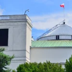Budynek Sejmu RP w Warszawie z charakterystyczną kopułą i polską flagą na dachu.