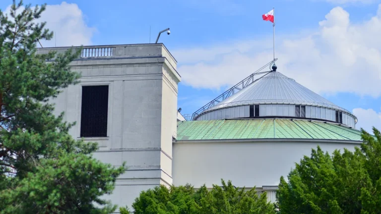 Budynek Sejmu RP w Warszawie z charakterystyczną kopułą i polską flagą na dachu.